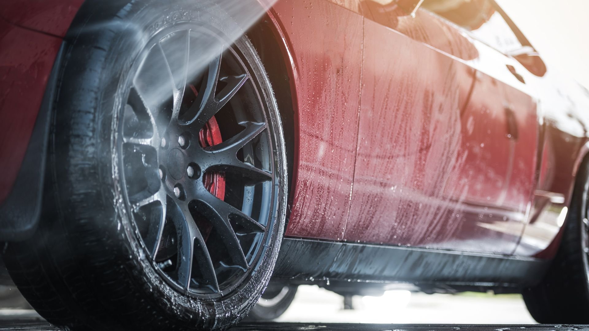 Wet red car with detailed alloy wheel and water droplets