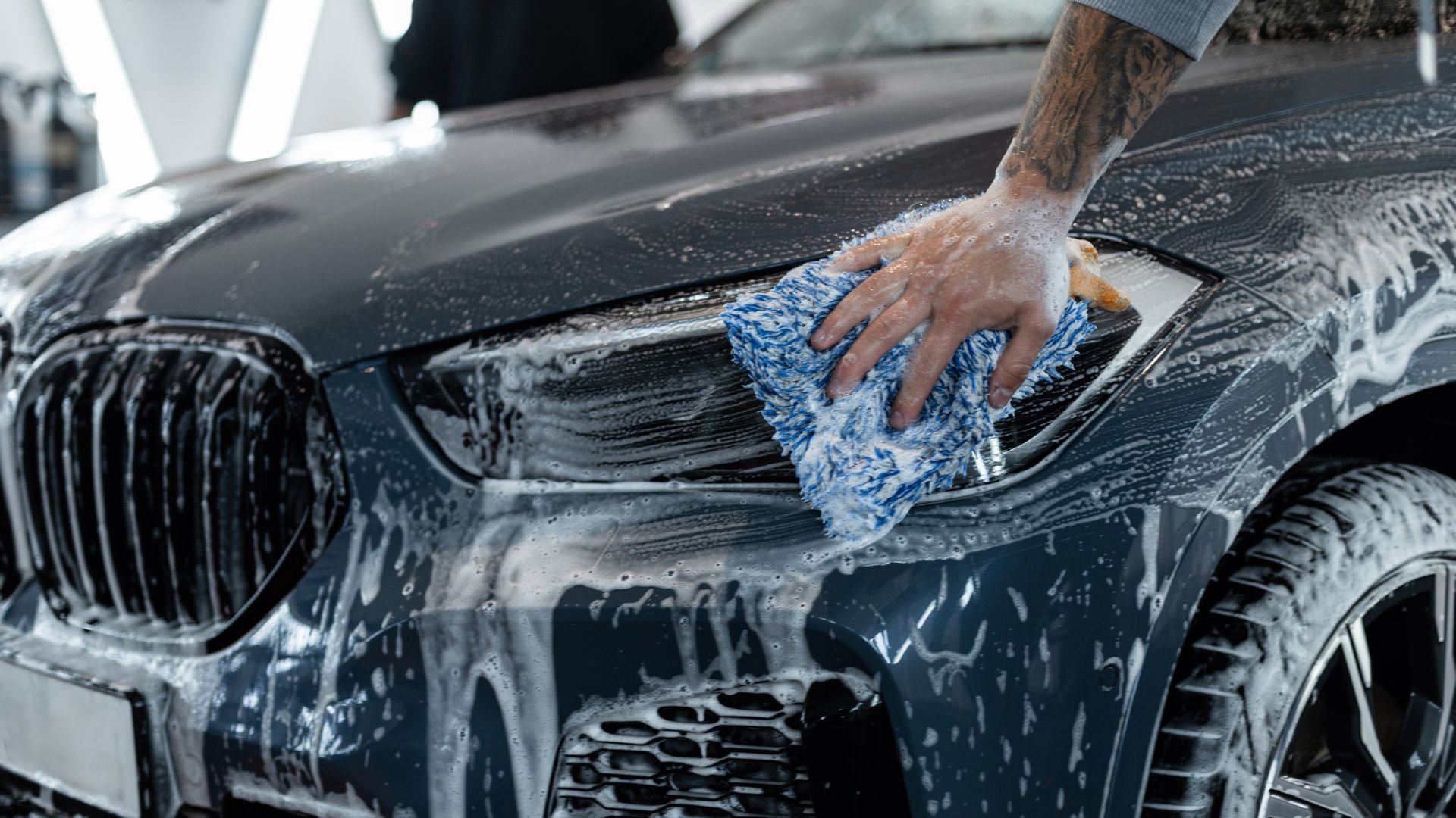 Hand washing BMW car with blue and white microfiber cloth