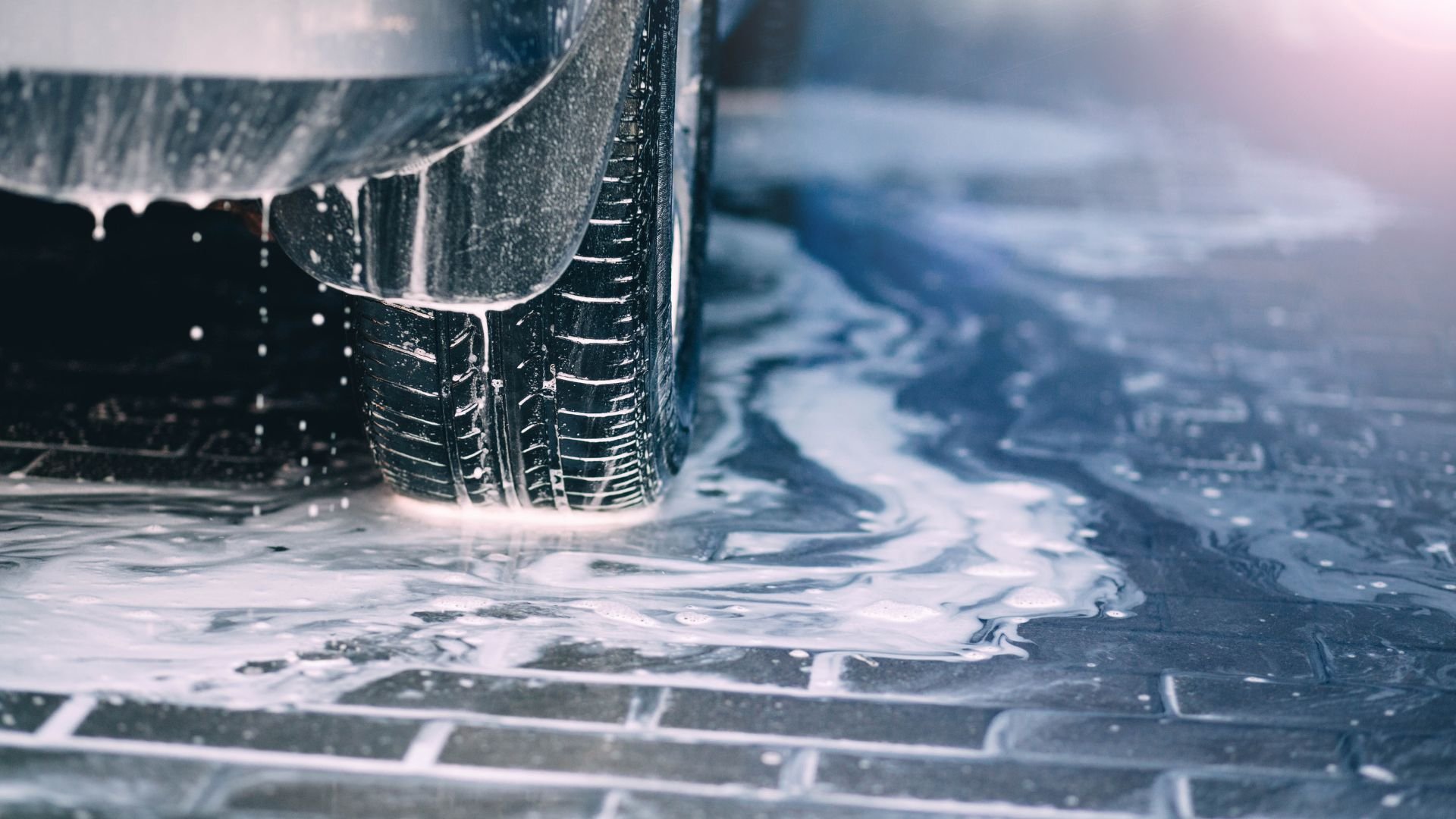 Car tire on wet, icy surface with water droplets and reflections