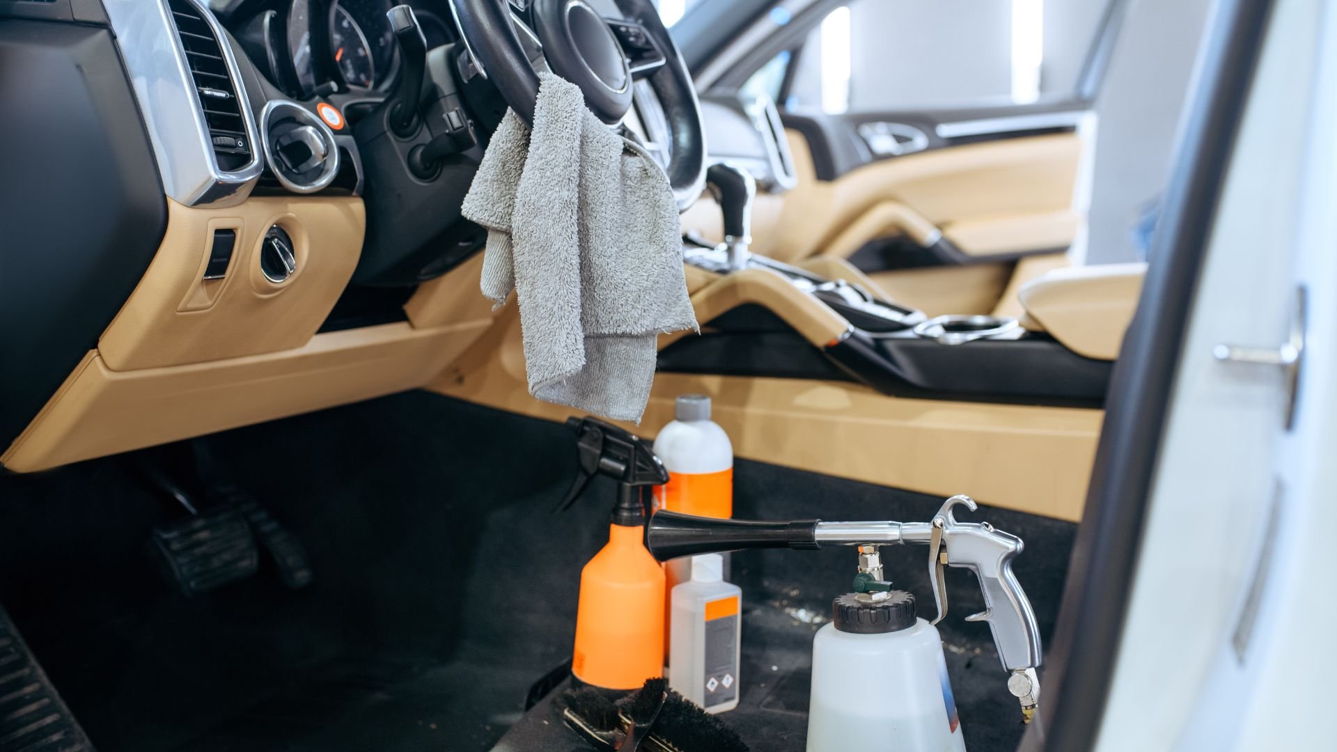 Car interior with cleaning supplies, spray bottles, and microfiber cloth